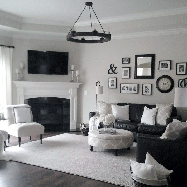 Living room with black leather sofa, white corner fireplace, gallery wall, and TV above mantel