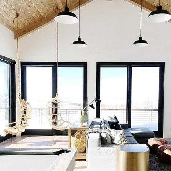 Spacious living room with hanging chairs, large windows, and modern decor elements.