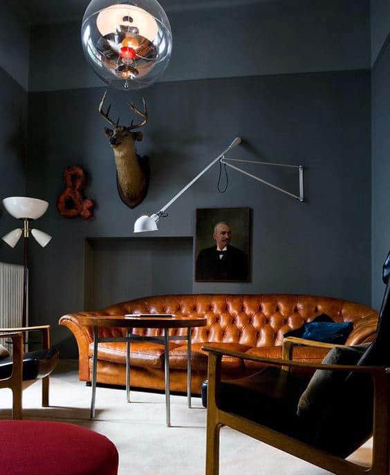 Living room with vintage brown leather sofa, mounted deer head, and eclectic decor accents.