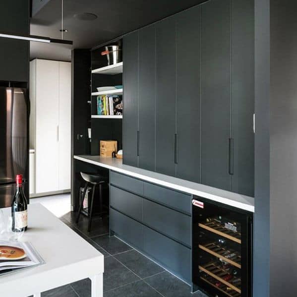Modern black kitchen with sleek cabinets, open shelves, white countertop, and wine cooler.