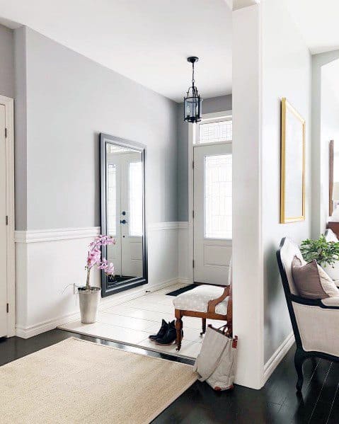 Chic entryway with white chair rail molding, light gray walls, a full-length mirror, and a classic bench for a welcoming vibe