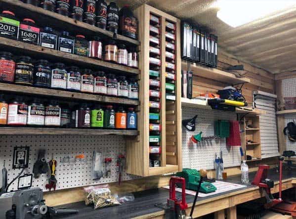 Highly organized reloading bench with wooden shelves, labeled storage for powders and primers, and tools on pegboards