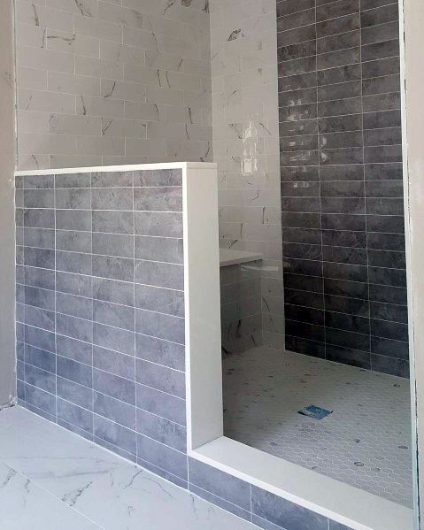 Modern bathroom shower with gray and white tiles, a sleek floor, and a partial dividing wall