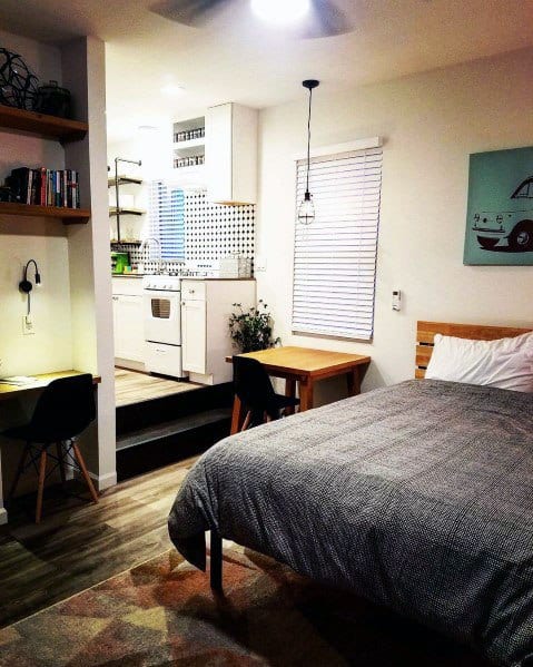 Cozy studio with elevated kitchen, workspace, dining table, and comfortable bed.