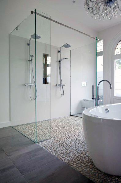 Modern bathroom with white glass shower, freestanding bathtub, and pebble floor
