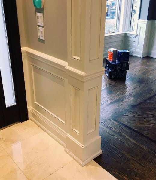 Luxurious foyer with detailed chair rail molding, marble flooring, and dark hardwood in adjoining spaces for a refined look