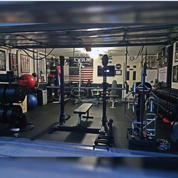 Compact garage gym with weights, bench press, dumbbells, and functional training equipment.