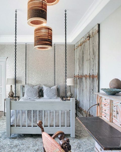 Farmhouse-style hanging bed with chain supports, rustic decor, and a weathered barn door accent.