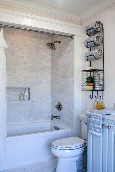 Cozy bathroom with marble tile shower, built-in niche, and towel storage rack.