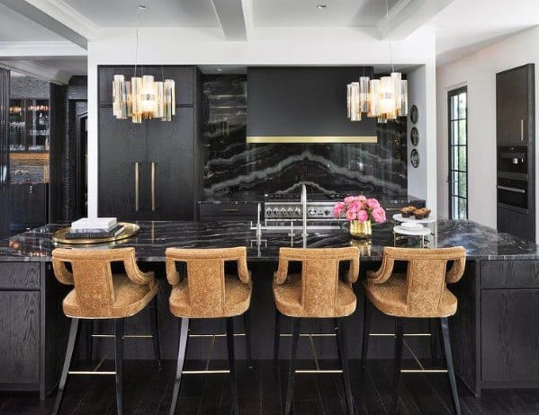 Black kitchen with marble countertops, gold accents, luxurious bar stools, and pendant lights.