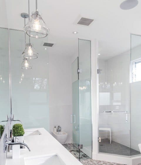 Corner bathroom featuring glass shower doors, hanging lights, and a sleek double sink