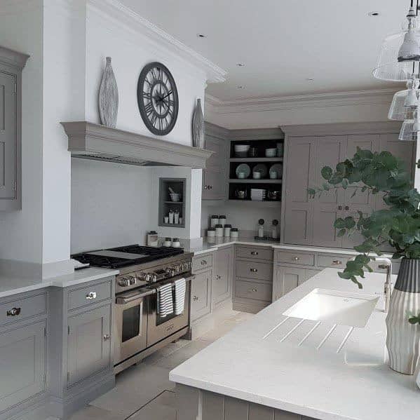 Traditional grey kitchen with open shelving, white countertops, and stainless steel appliances.