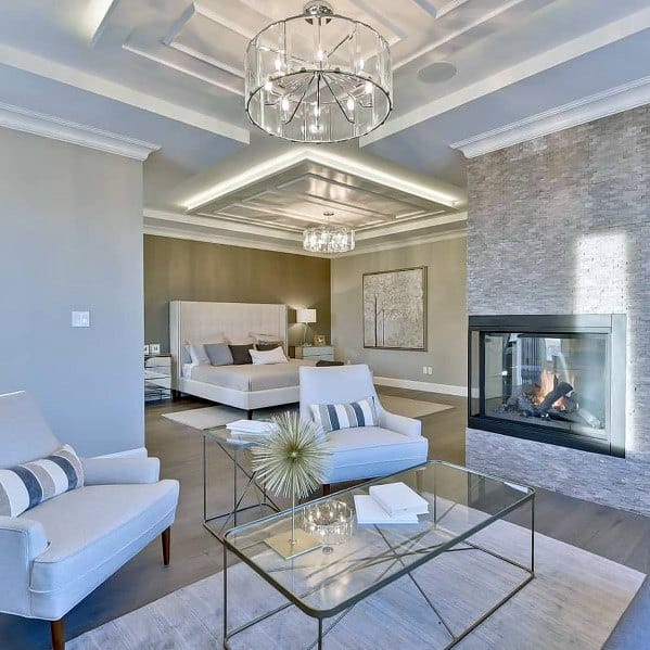 large luxury master bedroom with fireplace and glass coffee table 