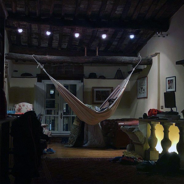 Hammock in a rustic living space with exposed wooden beams and warm ambient lighting.