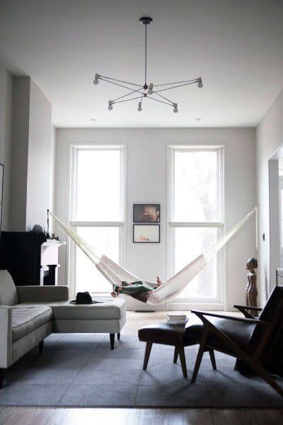 Minimalist living room with a hammock, modern furniture, and large windows for natural light.