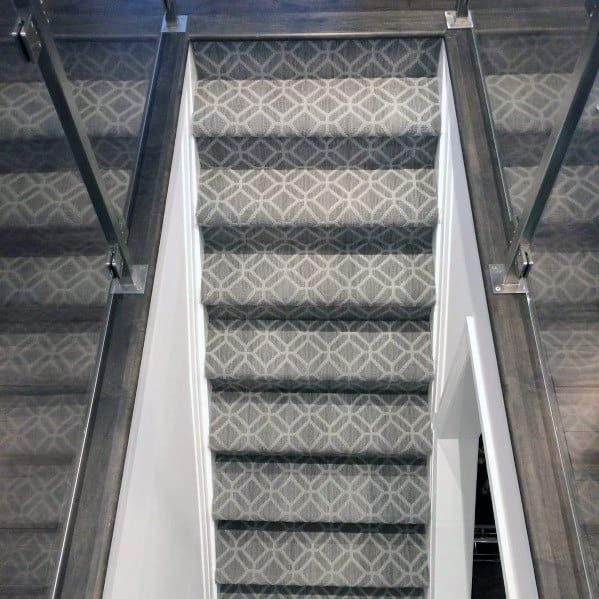 Carpeted staircase with geometric pattern and dark wood accents in a modern home design.