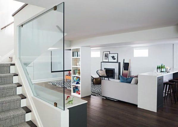 Carpeted staircase with glass panel railing leading to an open-plan living area in a modern home.