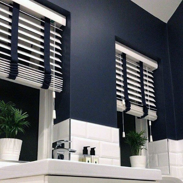 Bathroom with navy walls, white subway tiles, and matching white blinds.