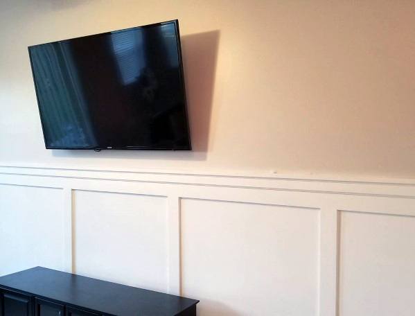 Minimalist living room with white chair rail molding, a wall-mounted TV, and a sleek black console for a modern touch