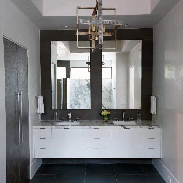 Luxurious bathroom with a floating white double vanity, marble countertop, large mirrors, and a geometric chandelier.