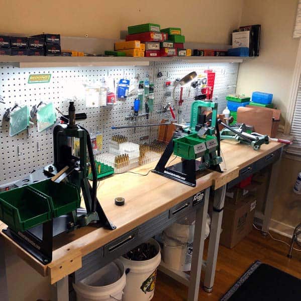 Efficient reloading bench with mounted presses, pegboard tool organization, and bright lighting for precision work