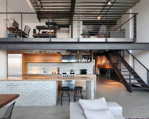 Modern loft with open kitchen, mezzanine office, exposed beams, and minimalist furniture.