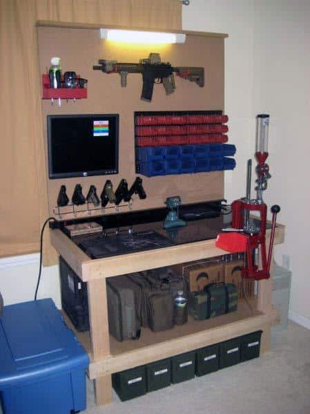 Compact reloading bench with mounted press, organized storage bins, and firearm display for a functional workspace