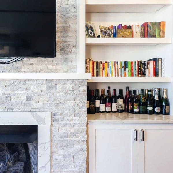 White stacked stone fireplace with built-in bookcases and a sleek bar area for a functional living space