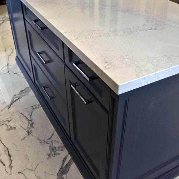 Dark grey kitchen cabinets with a marble countertop and matching marble flooring.