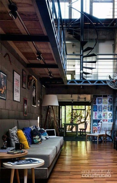 Industrial loft with exposed brick, spiral staircase, gallery wall, and wooden floors.
