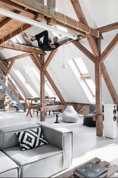 Loft space with exposed wooden beams, net hammock, skylights, and modern furniture.