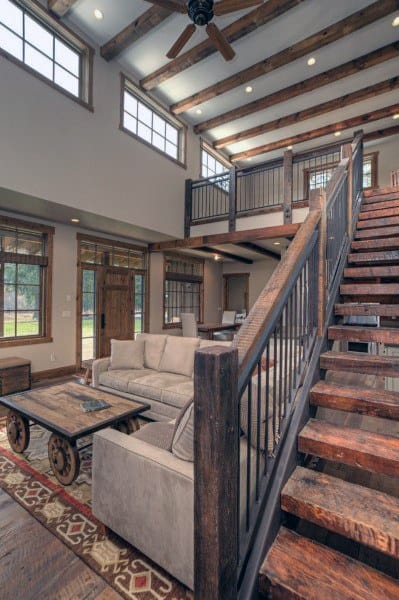 Rustic loft with wooden staircase, exposed beams, and cozy living area featuring vintage decor.