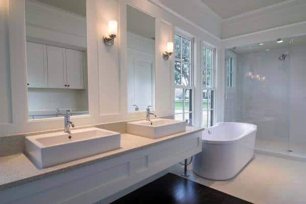 White modern bathroom with dual sinks, a freestanding tub, and large windows