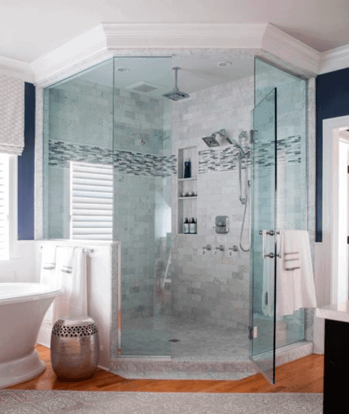 Modern bathroom with a glass-enclosed corner shower, white tub, and blue-gray tiled walls