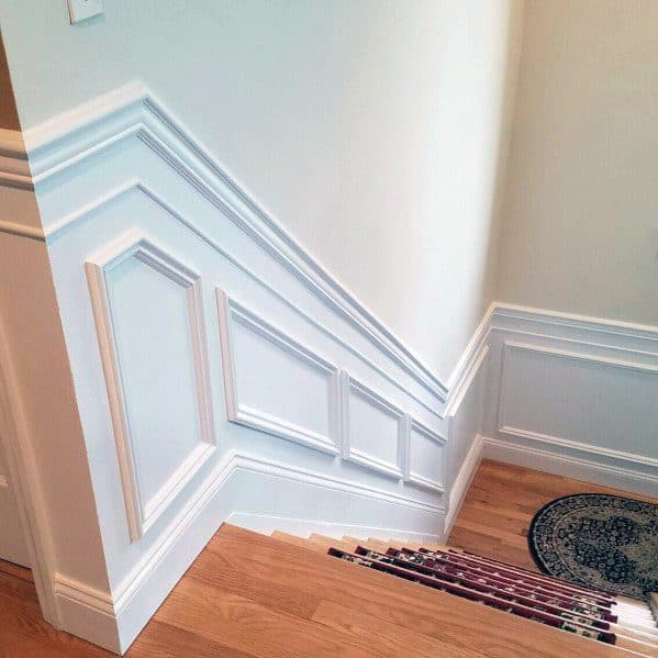 Elegant staircase with white chair rail molding, detailed trim panels, and light wood steps for a classic look