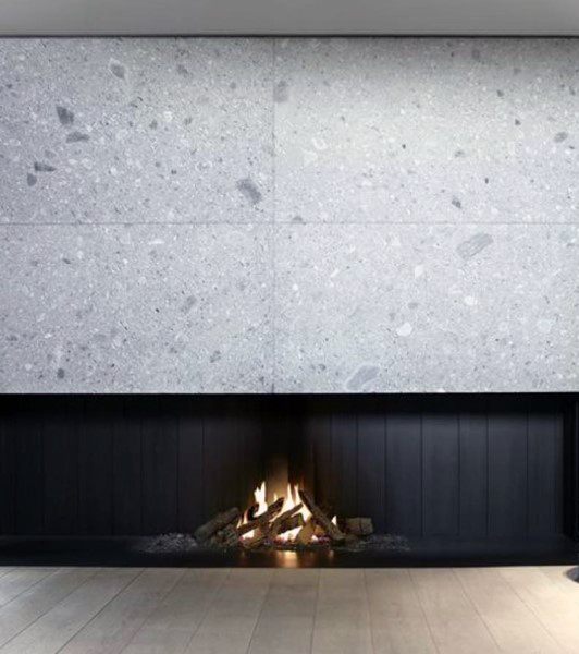 Minimalist fireplace with sleek black accents and a terrazzo stone surround.
