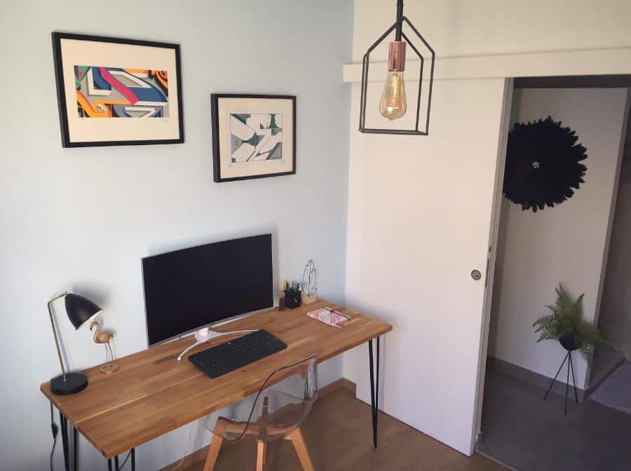 small home office brown desk clear plastic chair framed wall art