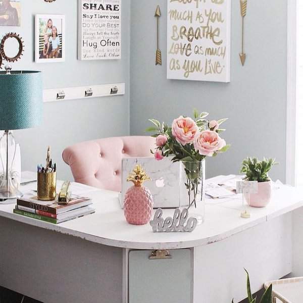 Bright home office with pastel pink furniture, inspirational wall art, fresh flowers, and personalized touches for a balanced feng shui environment.