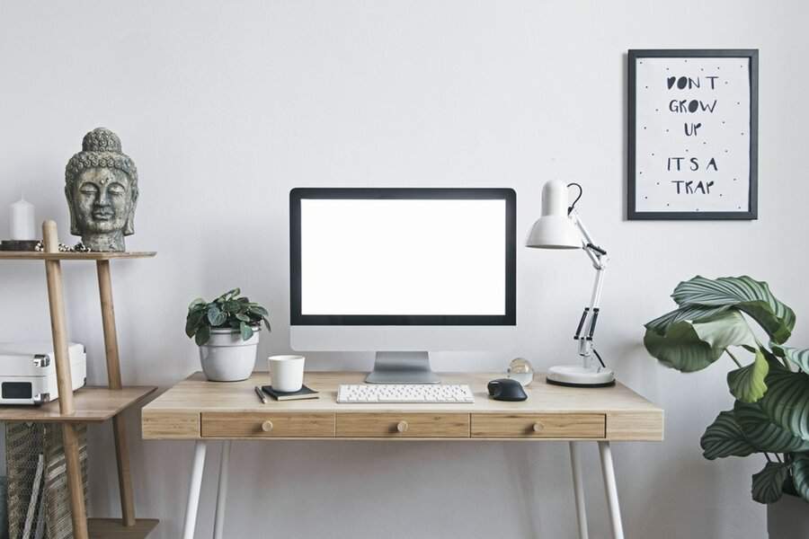 A minimalist desk with a plant, Buddha statue, and simple decor, creating a peaceful, focused workspace.