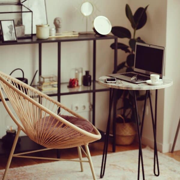 A stylish woven chair with a soft cushion, creating a comfortable and visually appealing focal point in a minimalist workspace.