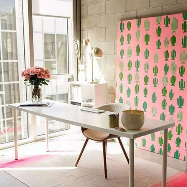 A bold cactus print backdrop energizes the workspace, providing a vibrant and playful focal point that complements the minimalist design