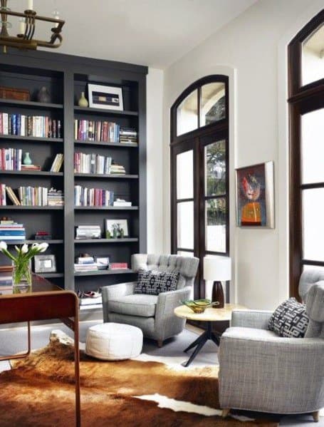 Cozy reading nook with comfy chairs, a bookshelf, and large windows