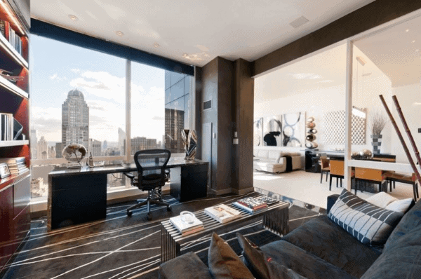 Luxury home office with city view, glass desk, ergonomic chair, and modern decor.