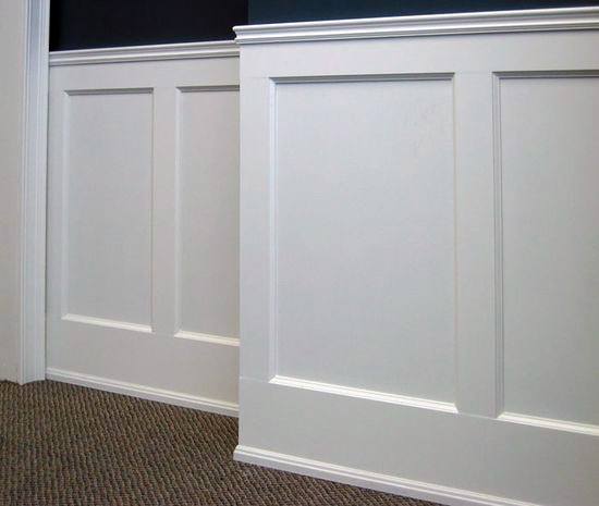 White wainscoting panels and a chair rail on a wall with a beige carpeted floor