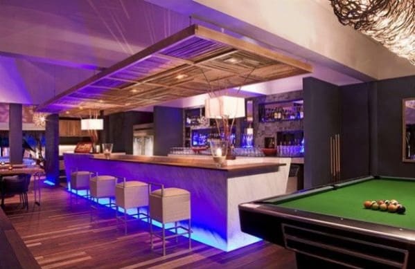 Chic bar interior with modern lighting, a marble counter, inviting stools, and a pool table in the foreground