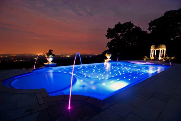 Home Swimming Pool At Night With Water Fountains And Neon Lighting