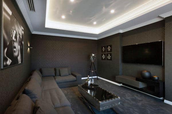 Modern living room with dark decor, a large sectional sofa, wall art, and a flat-screen TV for a home theater vibe