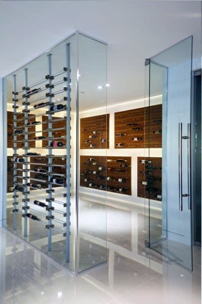 Modern wine cellar with glass walls, showcasing a curated array of wine bottles on elegant wooden racks