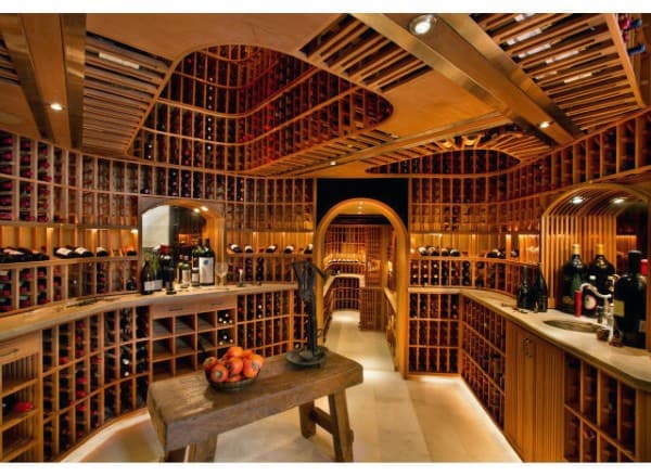 A cozy, well-lit wine cellar showcases wooden racks filled with wine bottles and a rustic table with fresh fruit