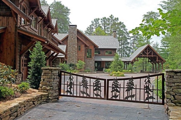 Metal driveway gate with forest silhouette design in a black frame.